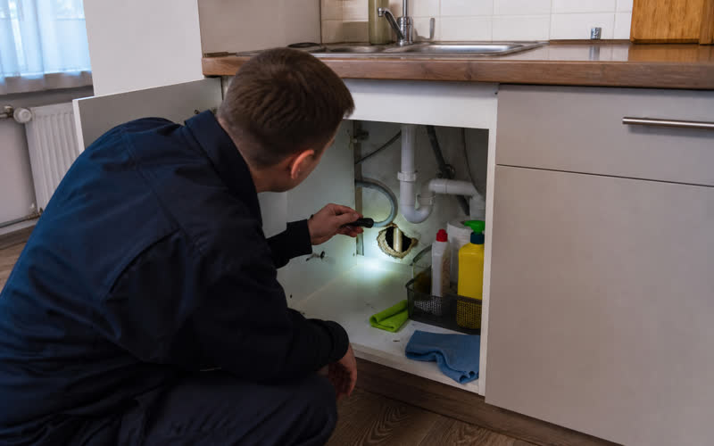 Inspection in a flat kitchen at the sink pipework